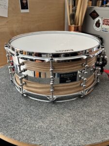 Steam-bent solid Ash snare drum with a natural hand-rubbed oil finish, featuring machined solid brass tube lugs , polished stainless steel inlay and chrome hardware